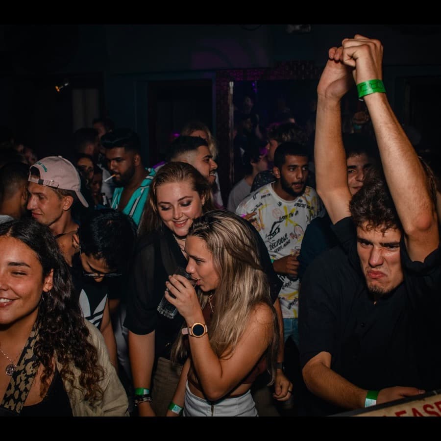 Members with their arms up in a packed room at a club night