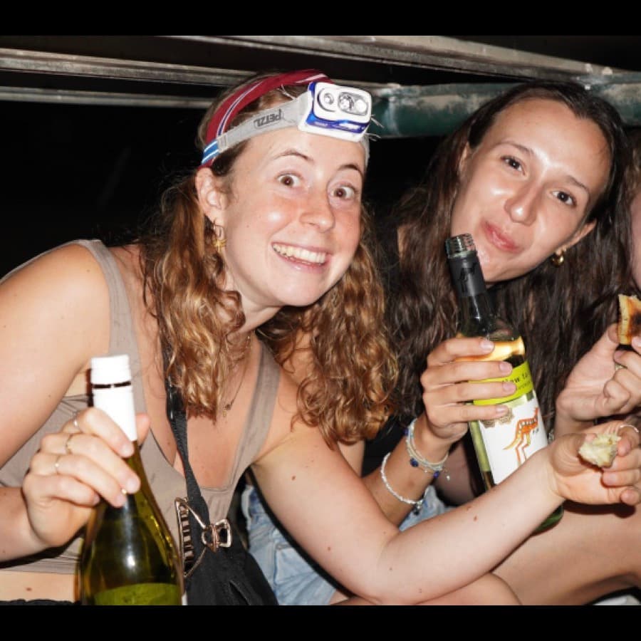 Two friends laughing with drinks at a club event